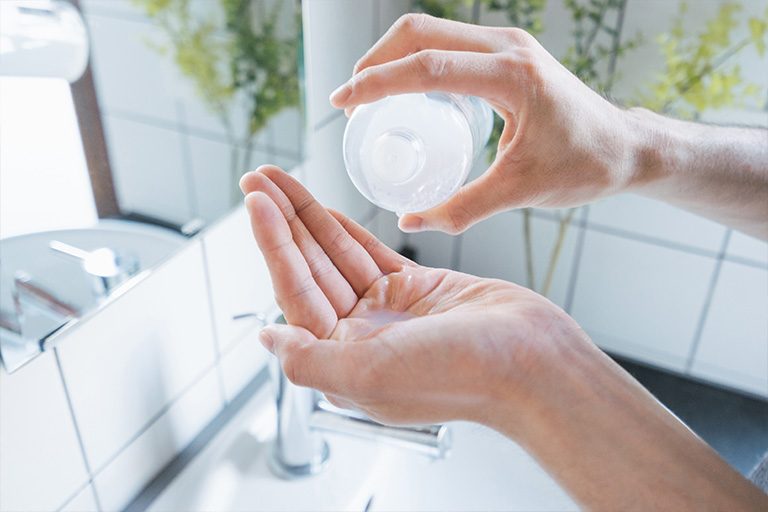 Eine Frau gießt Seife auf ihre Hand über dem Waschbecken. Das Helle, saubere Bad und das helle Licht im Hintergrund vermittelt hygiene und wohlbefinden.